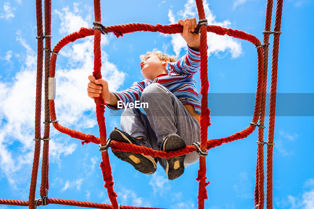 Low angle view of boy climbing on jungle gym