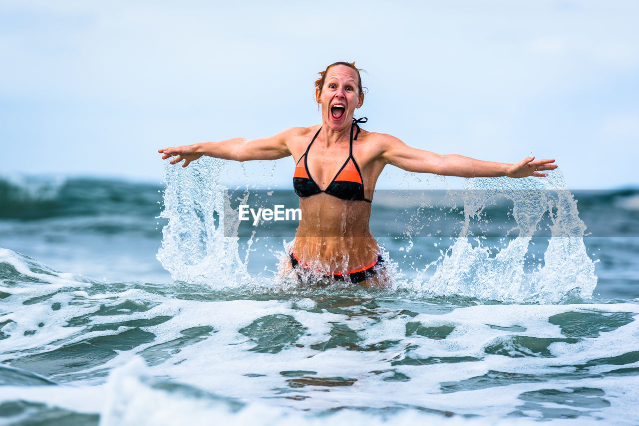 Portrait of happy woman standing in sea
