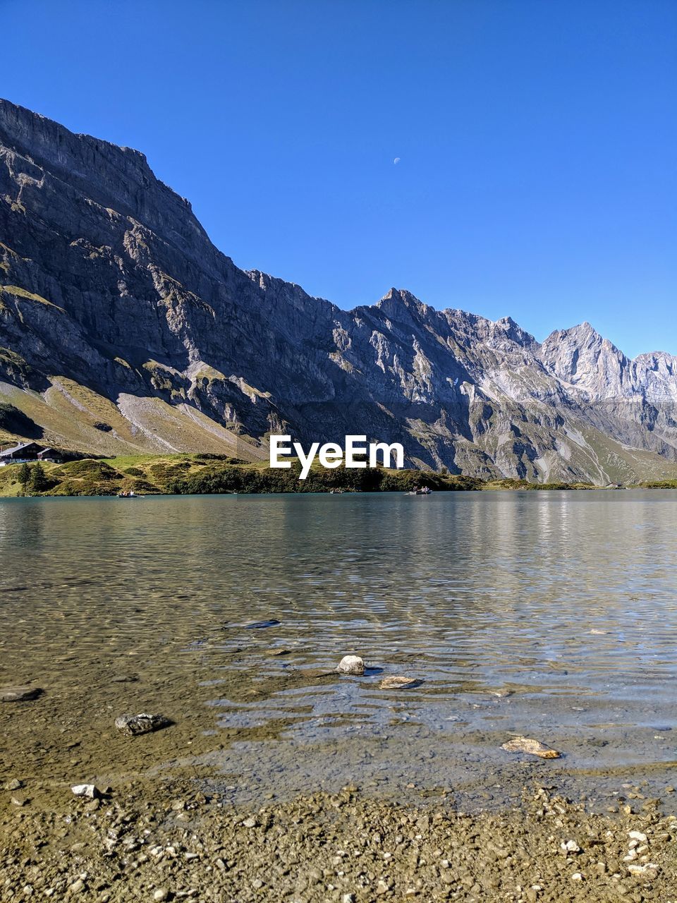 Scenic view of lake and mountains against clear blue sky