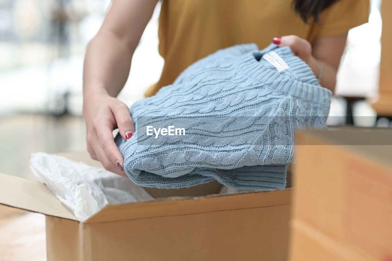 cardboard, cardboard box, box, adult, one person, moving house, women, young adult, indoors, beginnings, holding, casual clothing, packing, domestic room, container, relocation, home ownership, midsection, lifestyles, furniture, domestic life, female, business, unpacking, focus on foreground, paper, standing, day