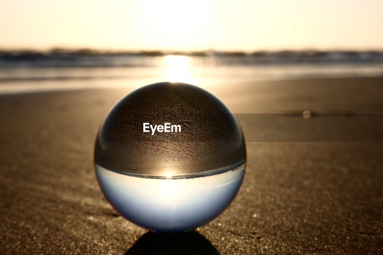 sea, light, reflection, land, beach, water, sky, sphere, nature, close-up, morning, sand, sunlight, single object, crystal ball, macro photography, focus on foreground, no people, horizon, blue, holiday, horizon over water, outdoors, black, white, lighting, ball, sports, scenics - nature, shiny, beauty in nature, tranquility, sun
