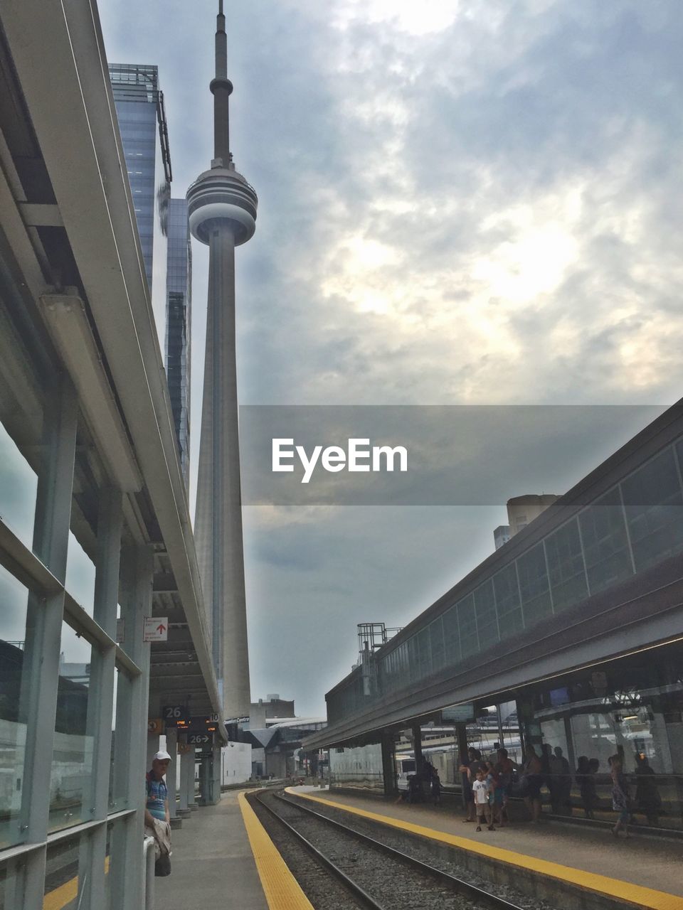 Railroad station by cn tower against cloudy sky