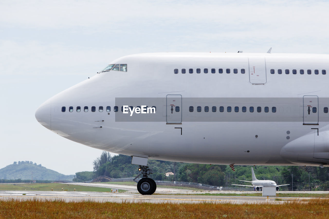 Airplane on airport runway against sky