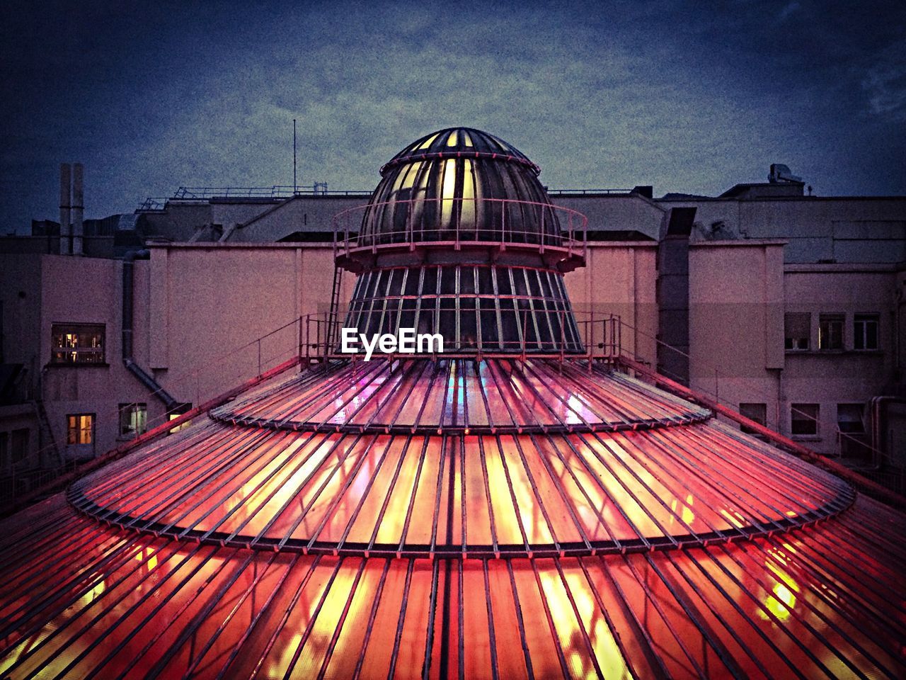 High section of roof of building lit up at dusk