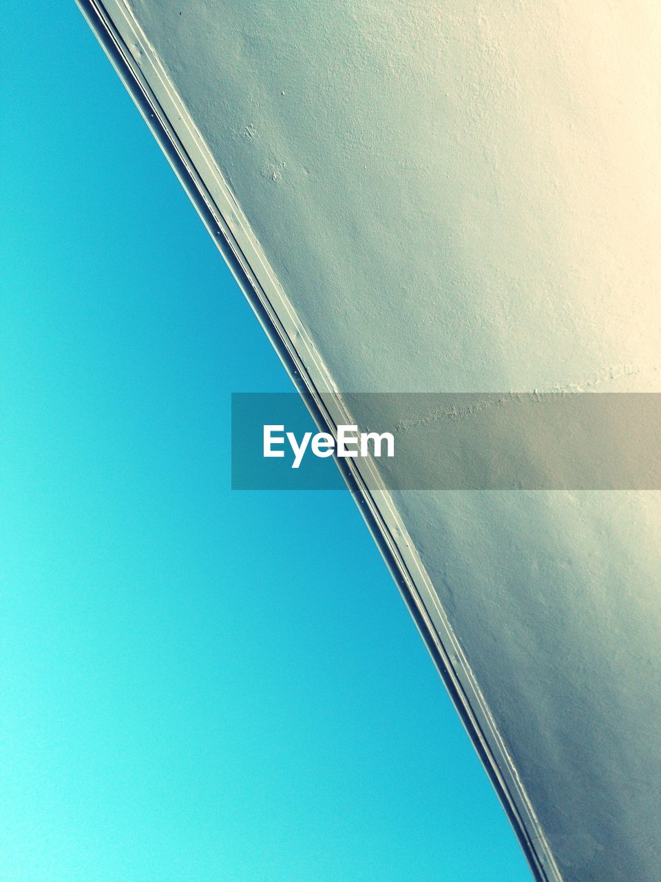 Tilt image of wall against clear blue sky