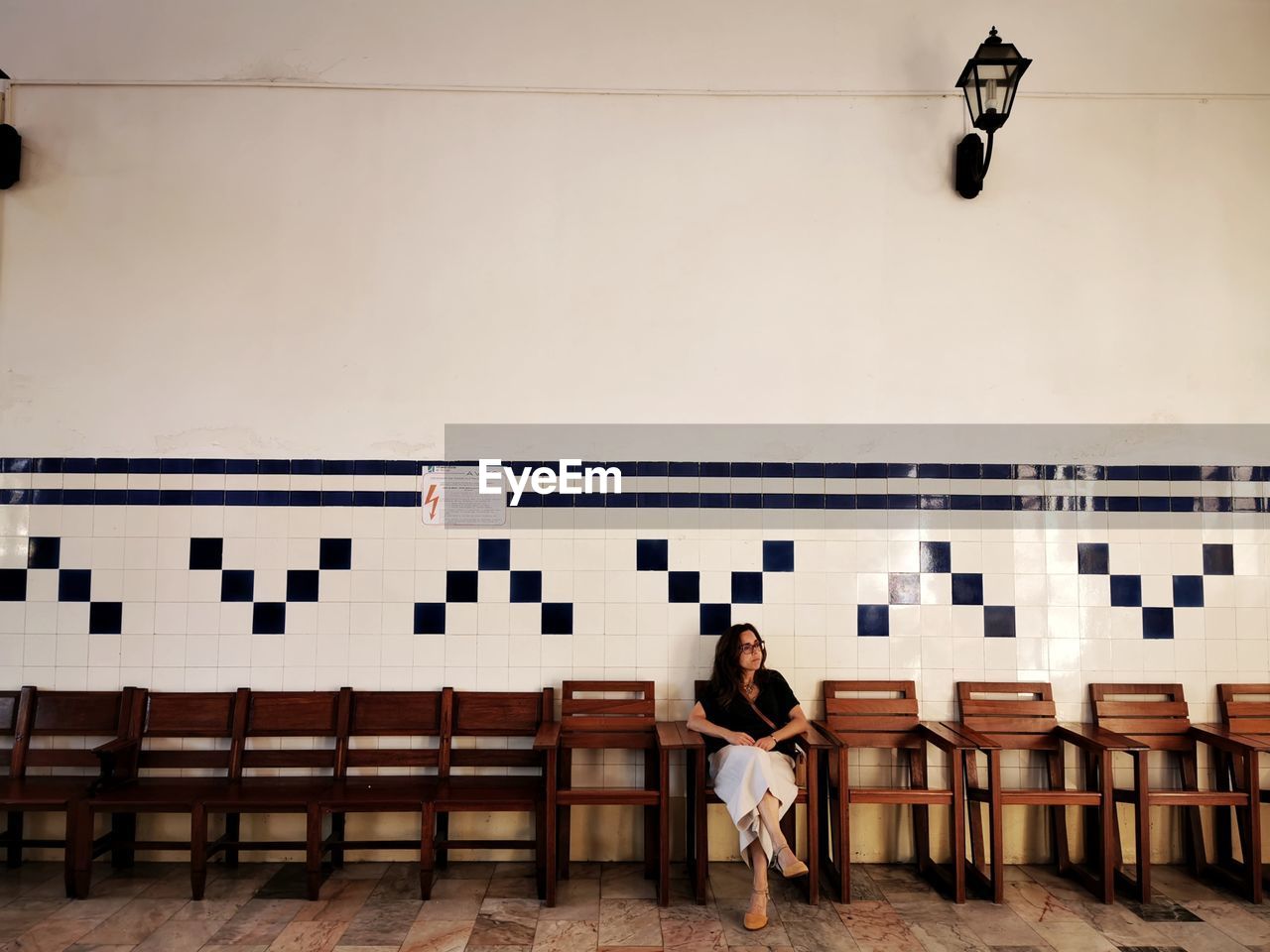 Woman sitting on chair against wall