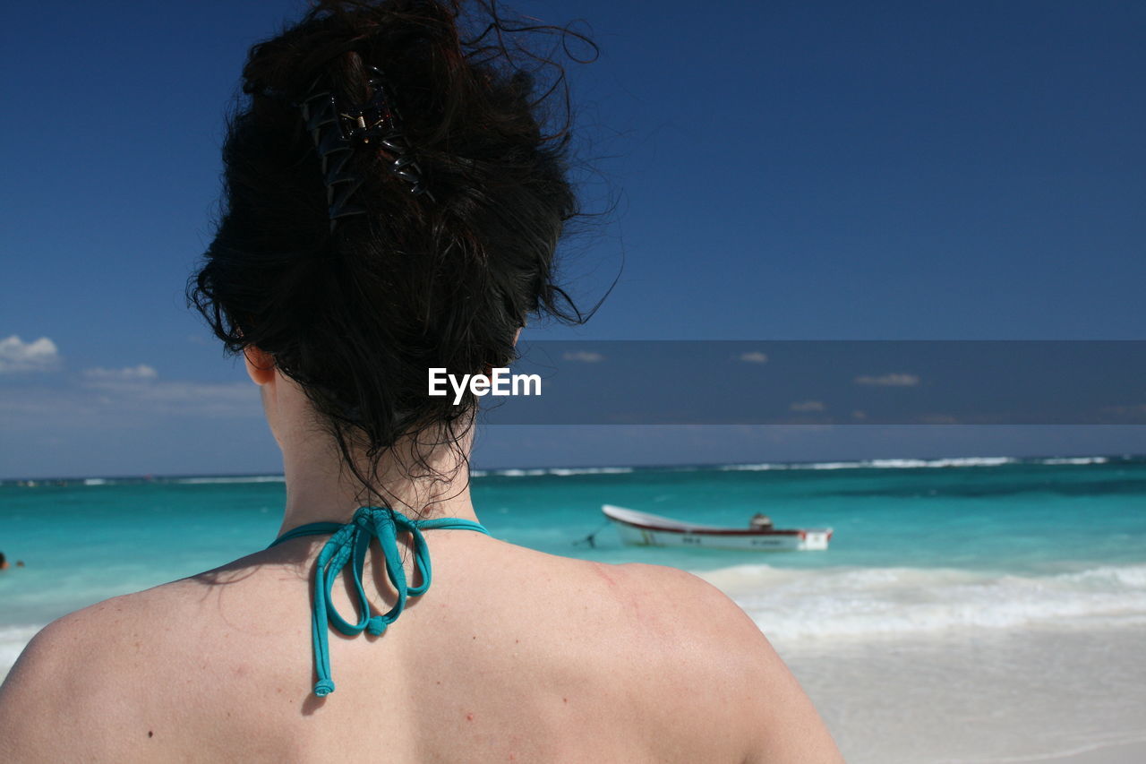 Rear view of woman on beach against sky