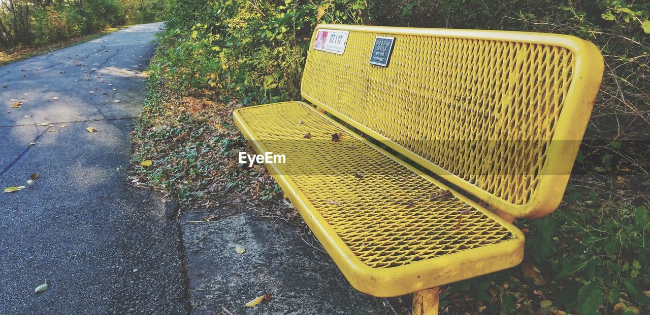 HIGH ANGLE VIEW OF EMPTY BENCH BY ROAD