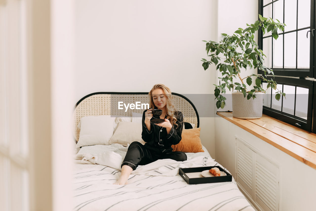 WOMAN SITTING ON BED AT HOME