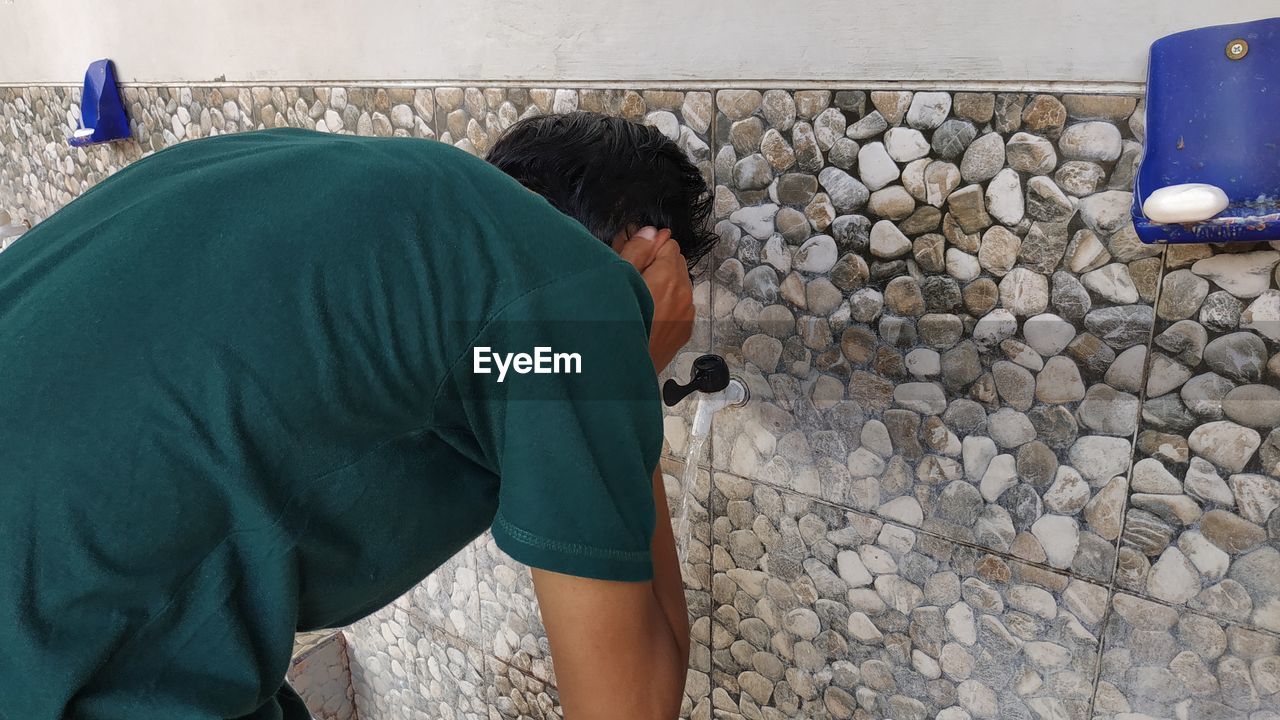 REAR VIEW OF MAN PHOTOGRAPHING WOMAN ON WALL