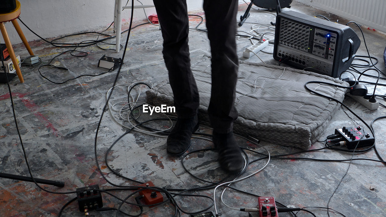 Low section of man standing amidst cables