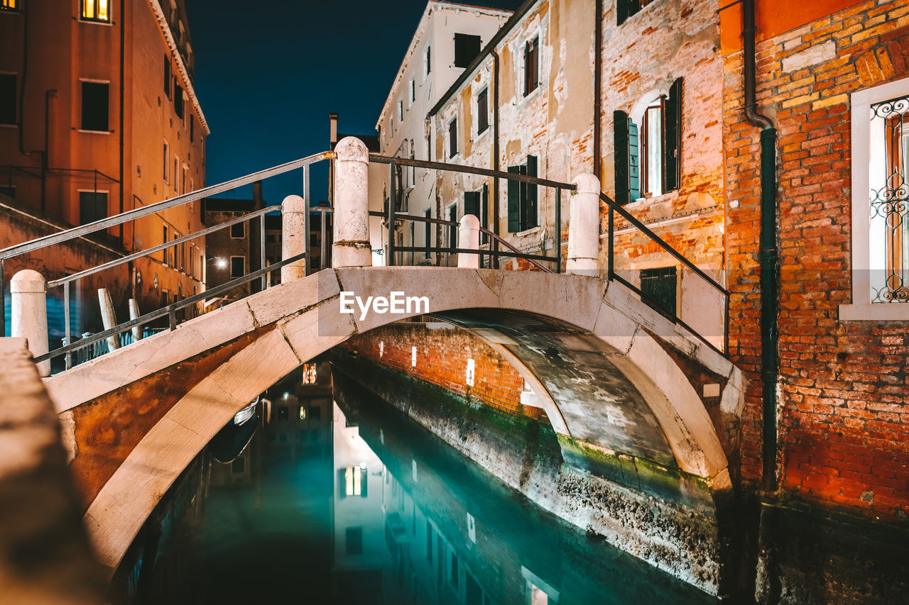 Arch bridge over canal in city at night