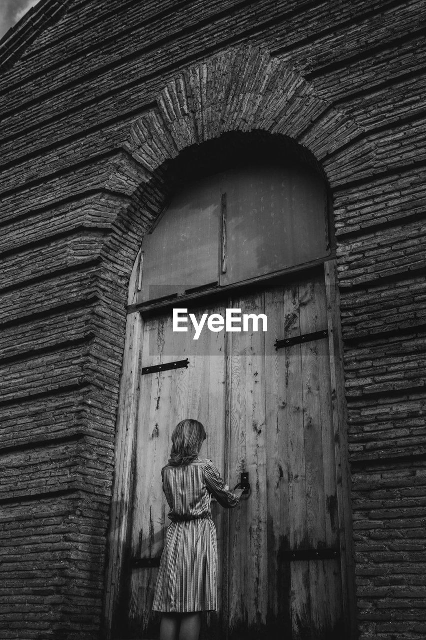 Rear view of woman standing by closed door