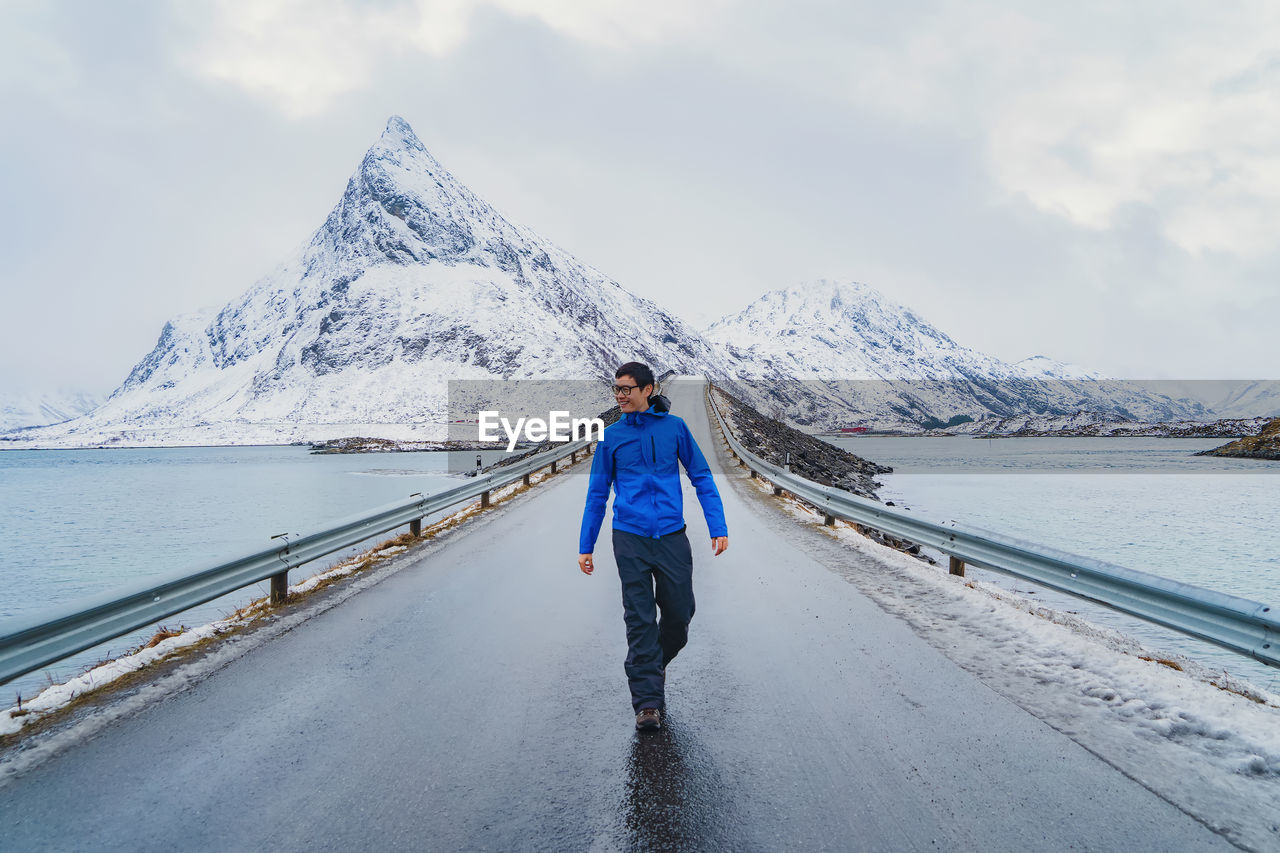 Full length of man walking on bridge over river during winter