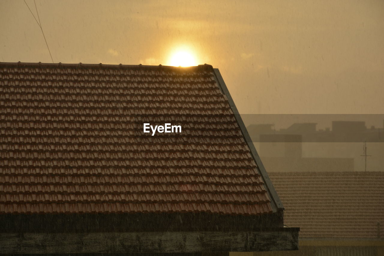 Roof of house against sky during sunset