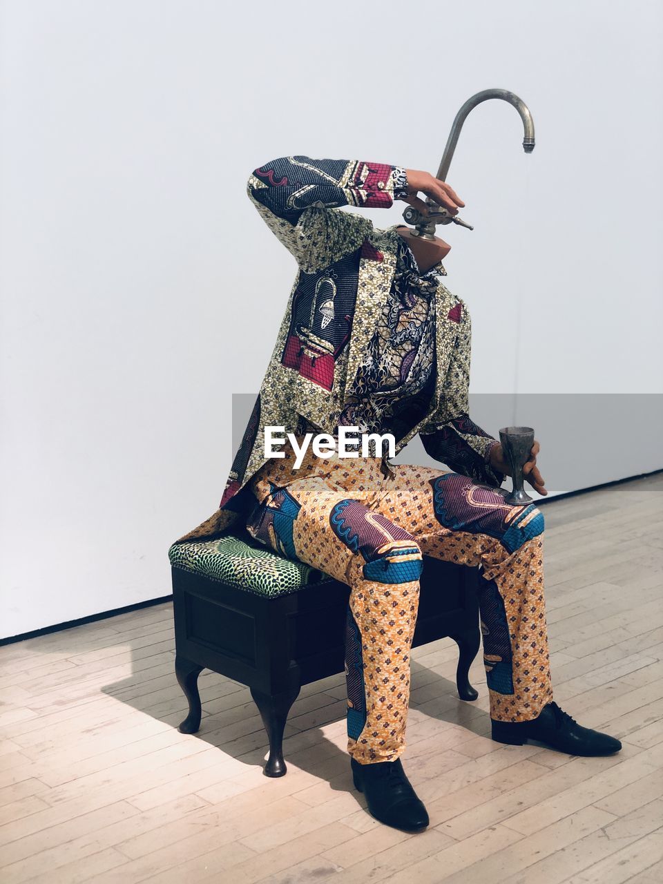 MAN SITTING ON CHAIR AGAINST WALL