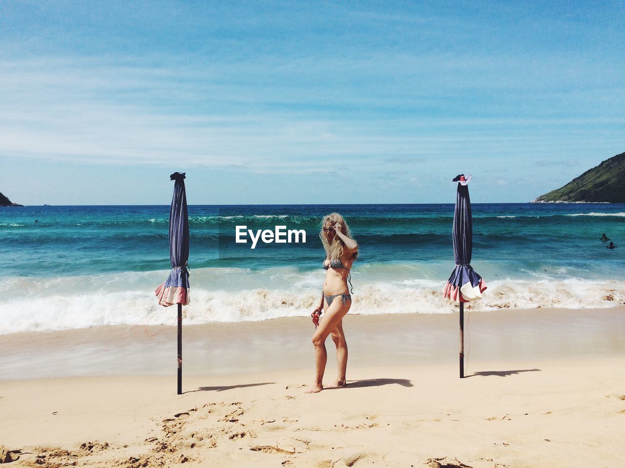 Full length of woman standing at beach against sky