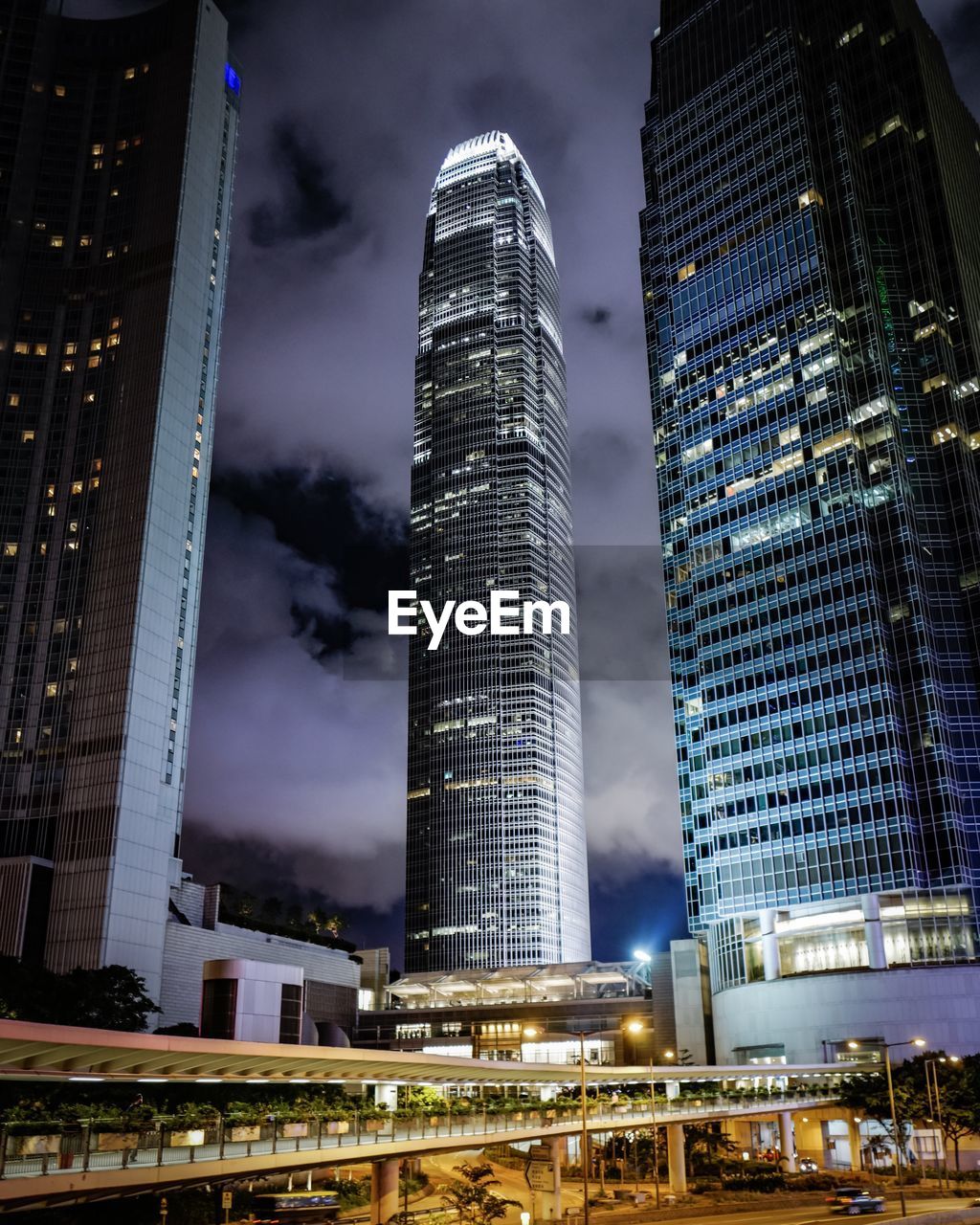 LOW ANGLE VIEW OF ILLUMINATED SKYSCRAPERS AGAINST CLOUDY SKY