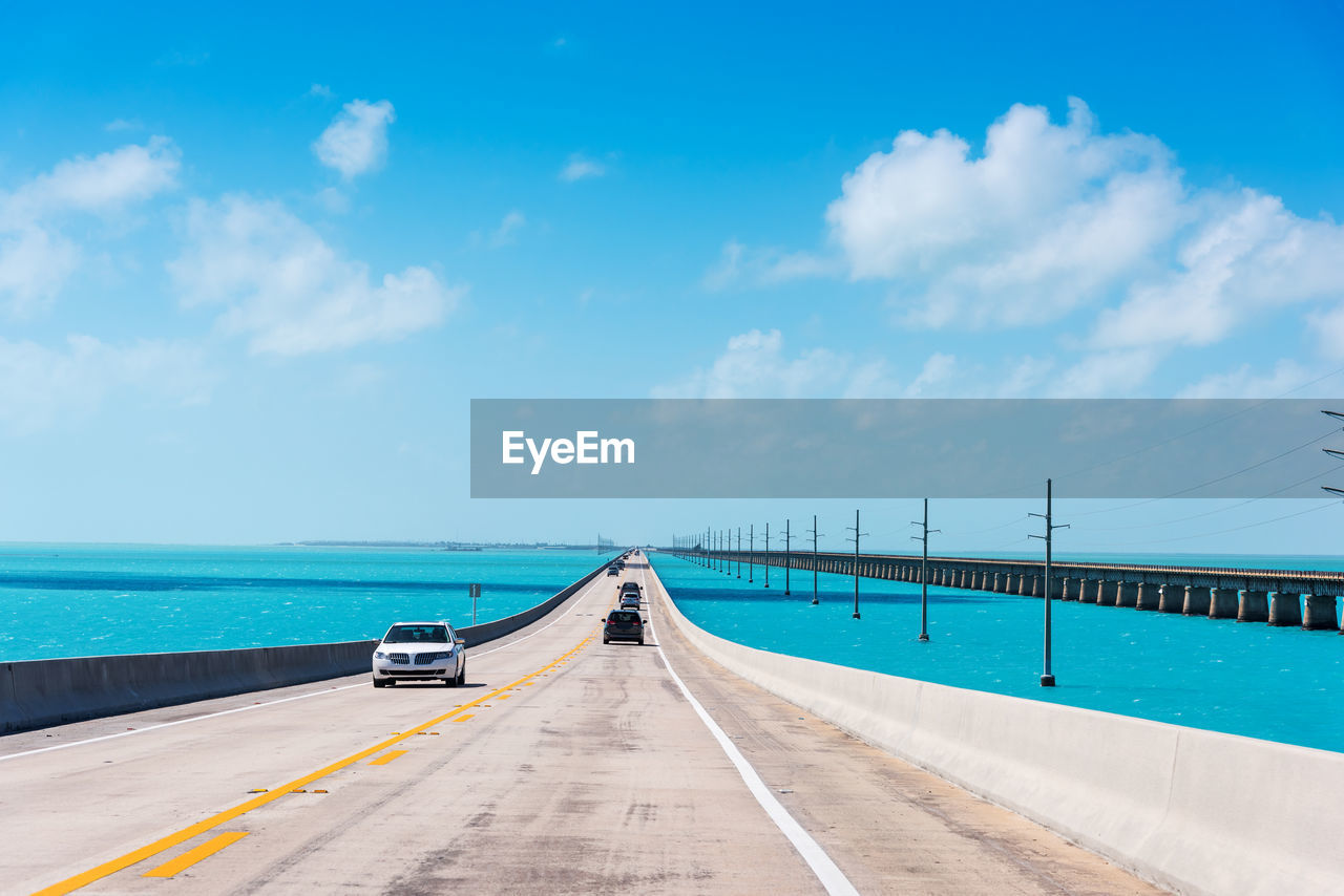 ROAD LEADING TOWARDS SEA AGAINST BLUE SKY