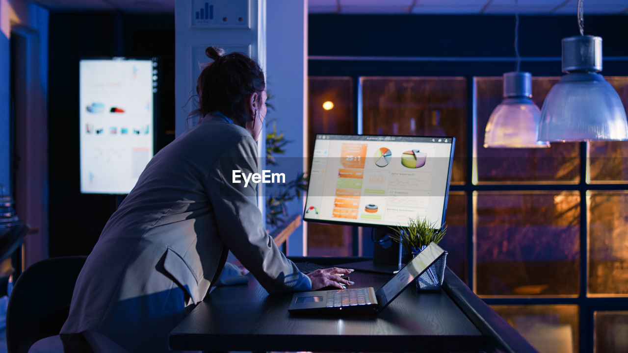 rear view of woman using digital tablet while standing in office