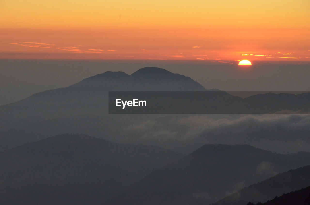 Scenic view of mountains in foggy weather during sunrise