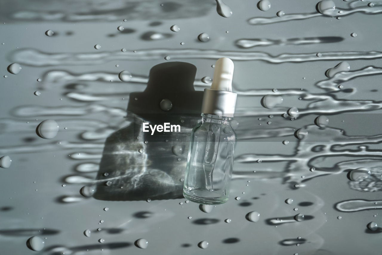 CLOSE-UP OF WATER DROPS ON GLASS AGAINST WHITE BACKGROUND