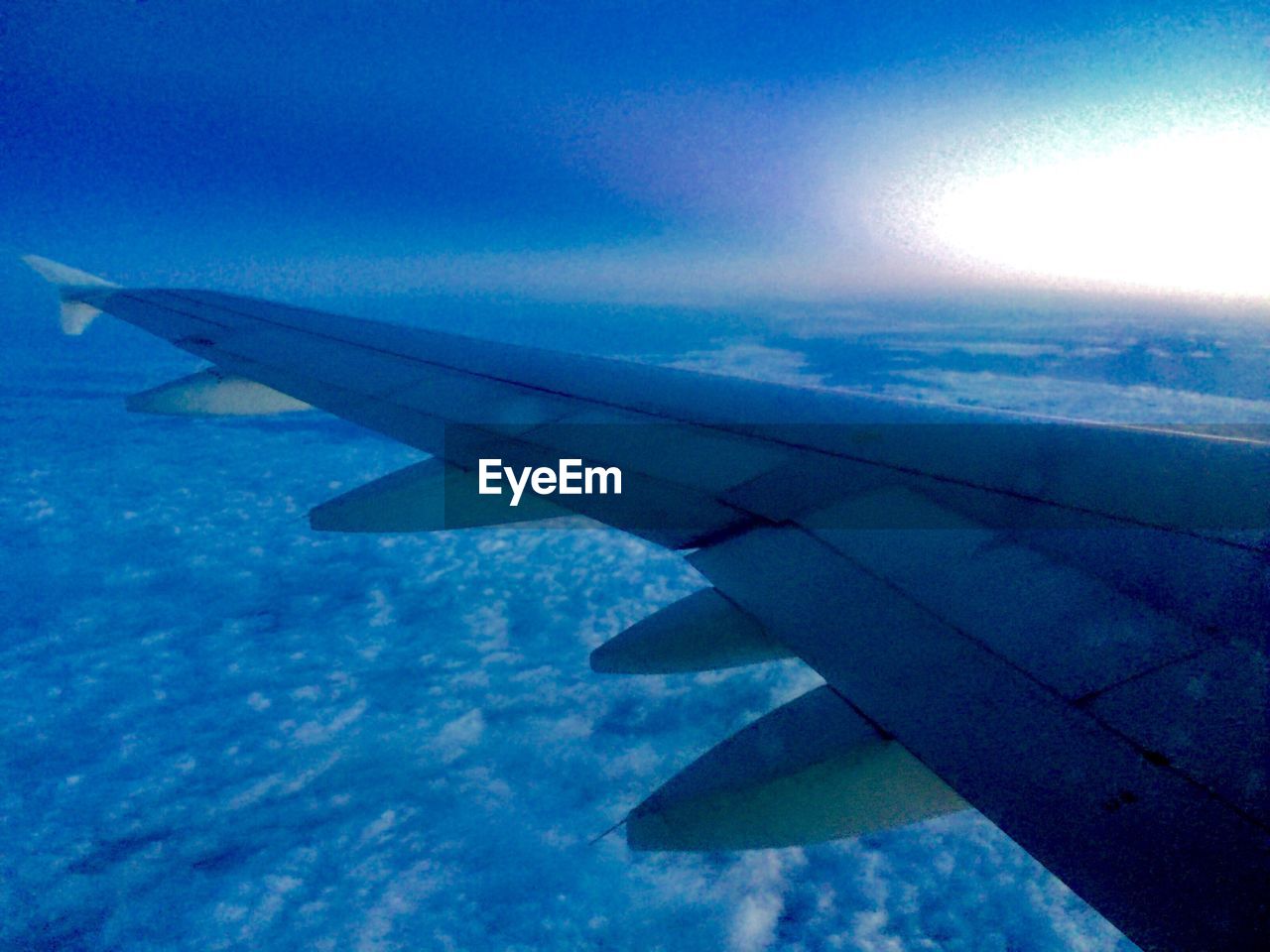 CROPPED IMAGE OF AIRPLANE WING OVER LANDSCAPE