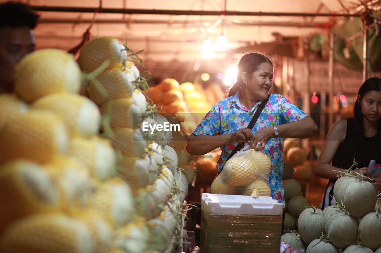 Woman buying cantaloupe at market