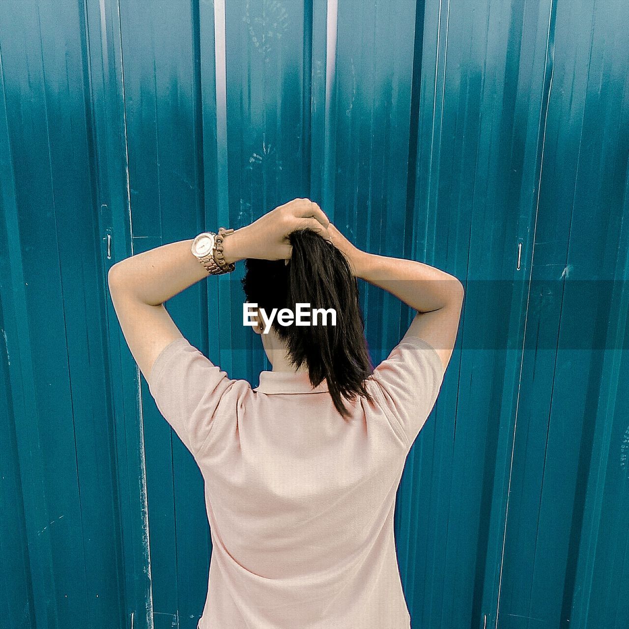 Rear view of young woman standing against wall