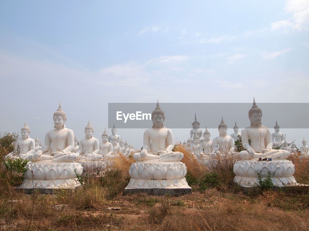 Buddha statues against sky on field