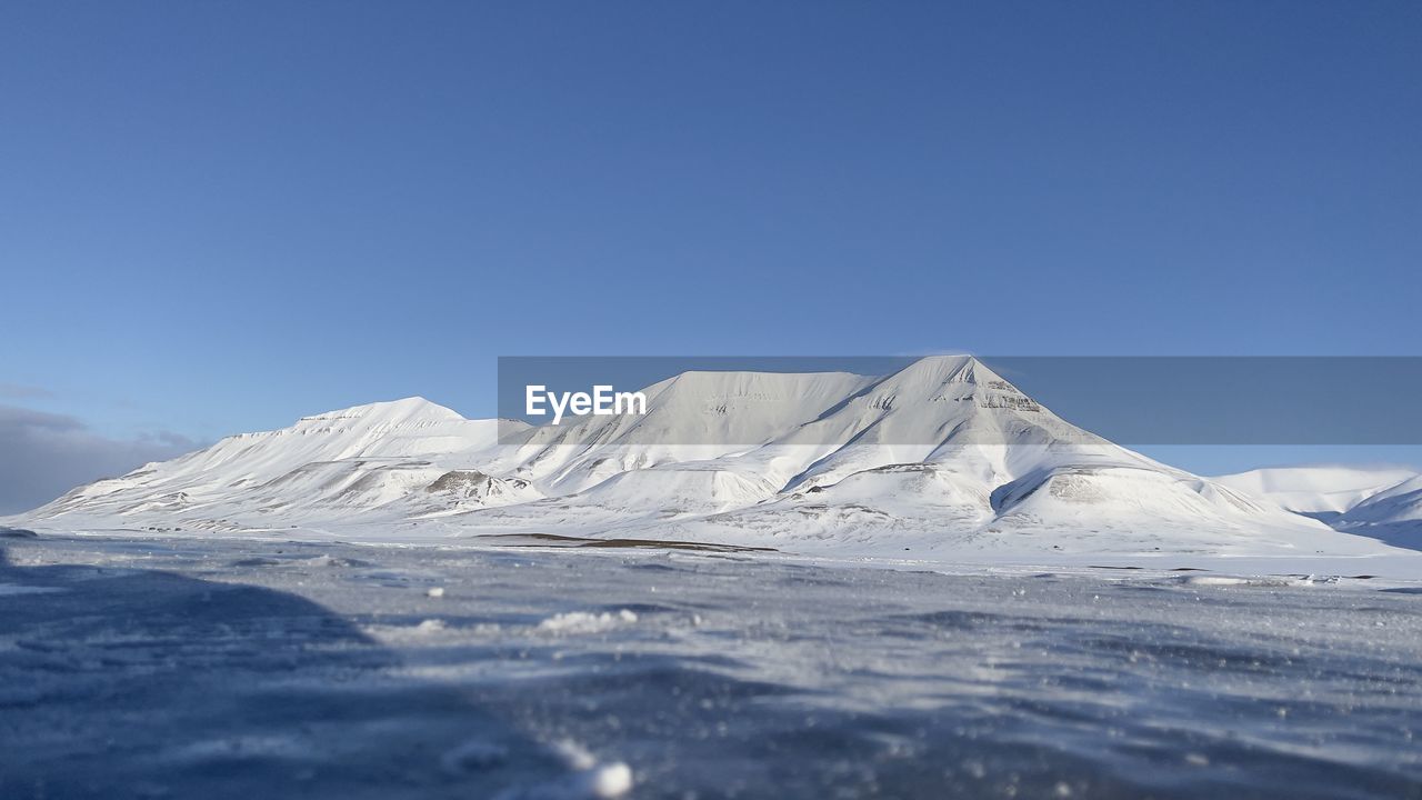 Scenic view of snowcapped mountains against clear blue sky -svalbard 