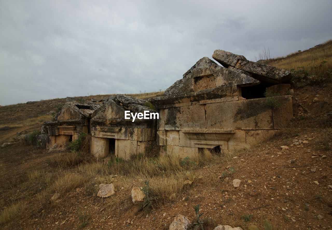 Ancient tombs on field against sky