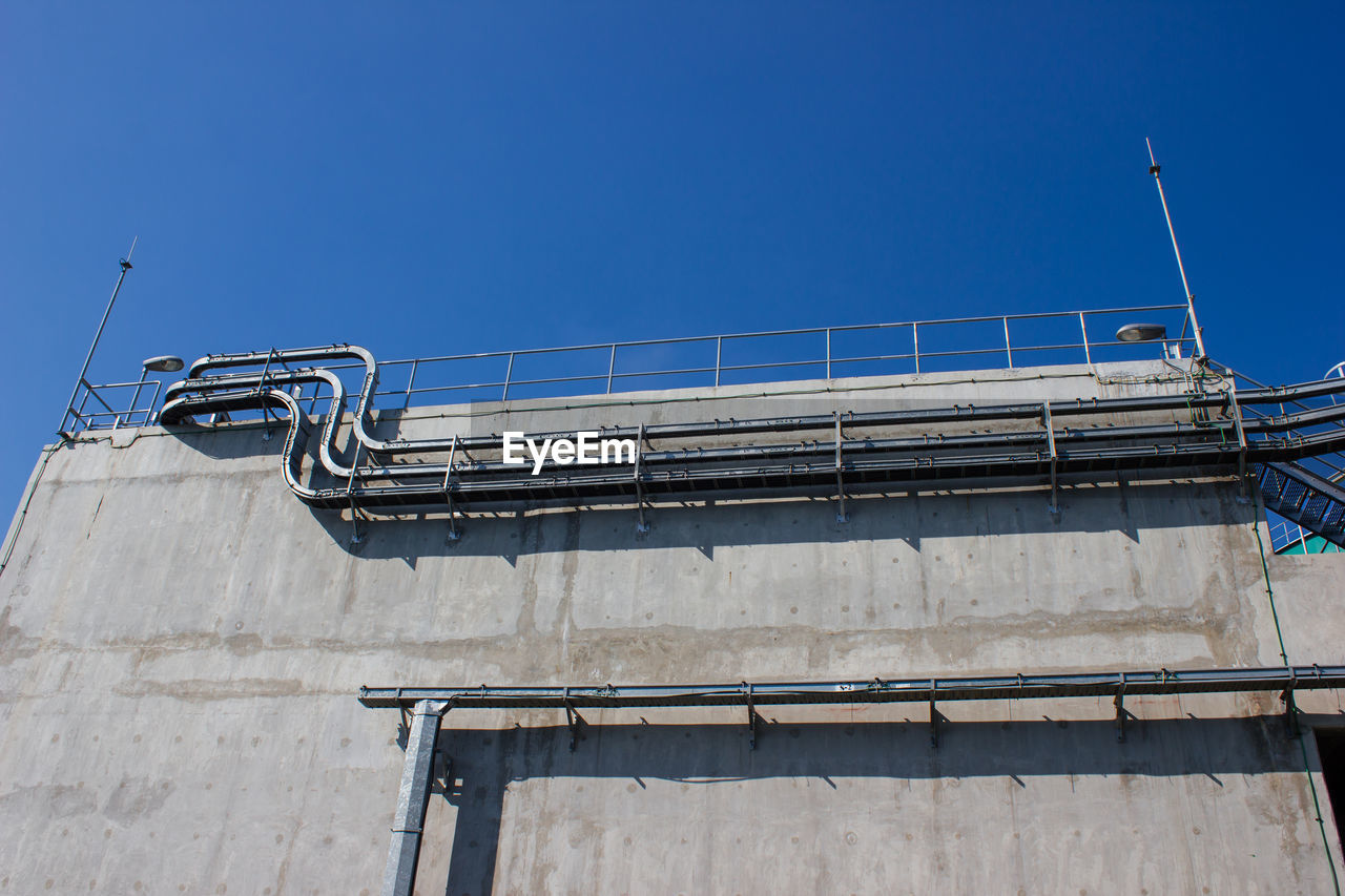 LOW ANGLE VIEW OF METALLIC STRUCTURE AGAINST BUILDING