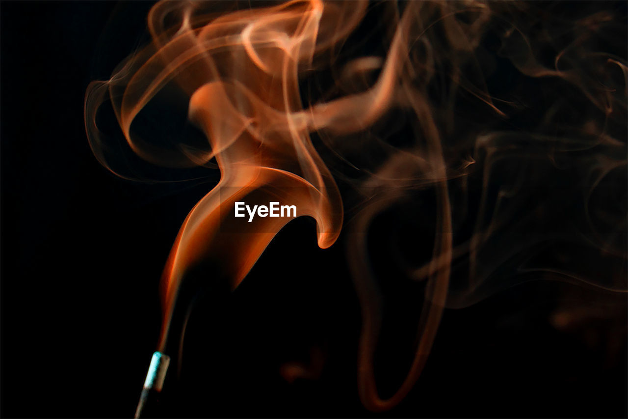 Close-up of smoke from incense stick against black background