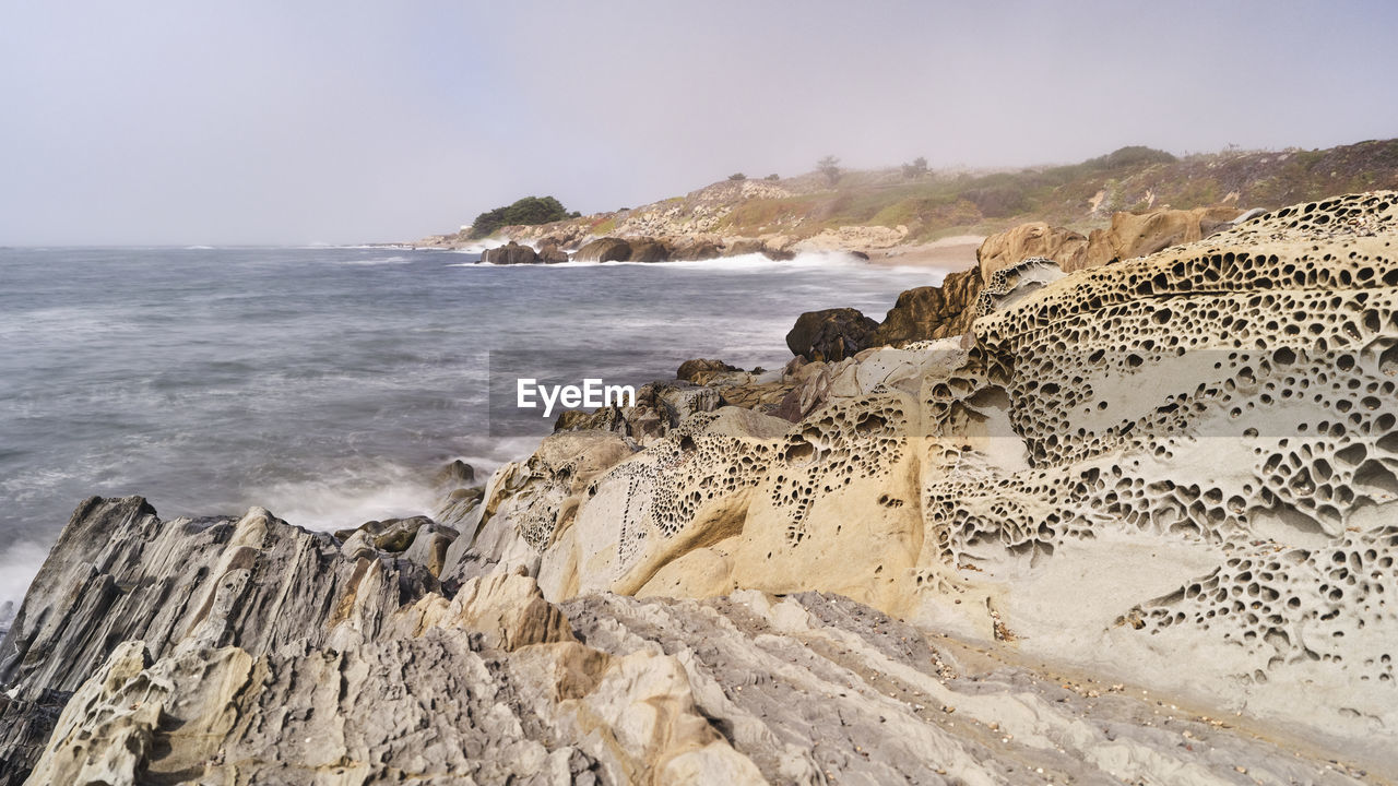 Tafoni rock and cavernous formation with sea against sky  bean hollow state beach, ca