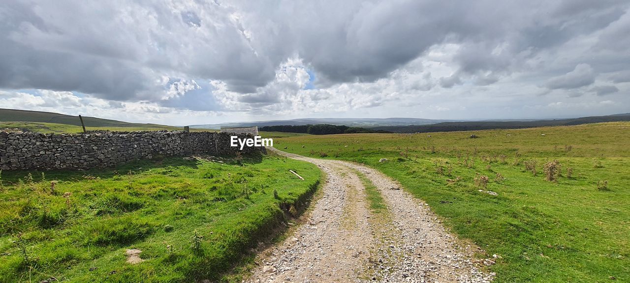 landscape, environment, cloud, sky, nature, land, grass, scenics - nature, plant, road, hill, field, beauty in nature, rural area, grassland, rural scene, travel, no people, green, footpath, dirt road, travel destinations, panoramic, transportation, plateau, horizon, meadow, tourism, dramatic sky, the way forward, tranquility, non-urban scene, outdoors, prairie, water, coast, dirt, cloudscape, agriculture, overcast, tranquil scene, storm, highland, plain, day