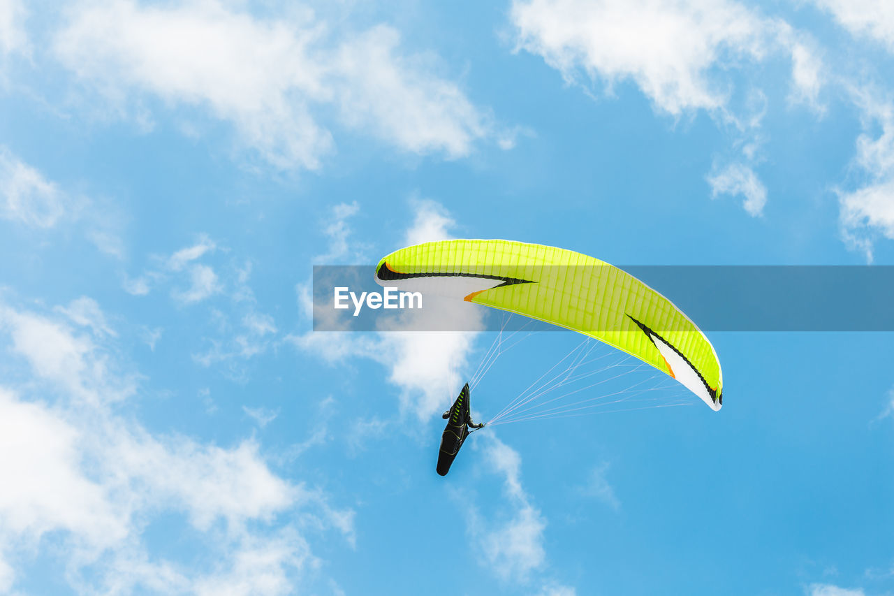 Low angle view of person paragliding against blue sky