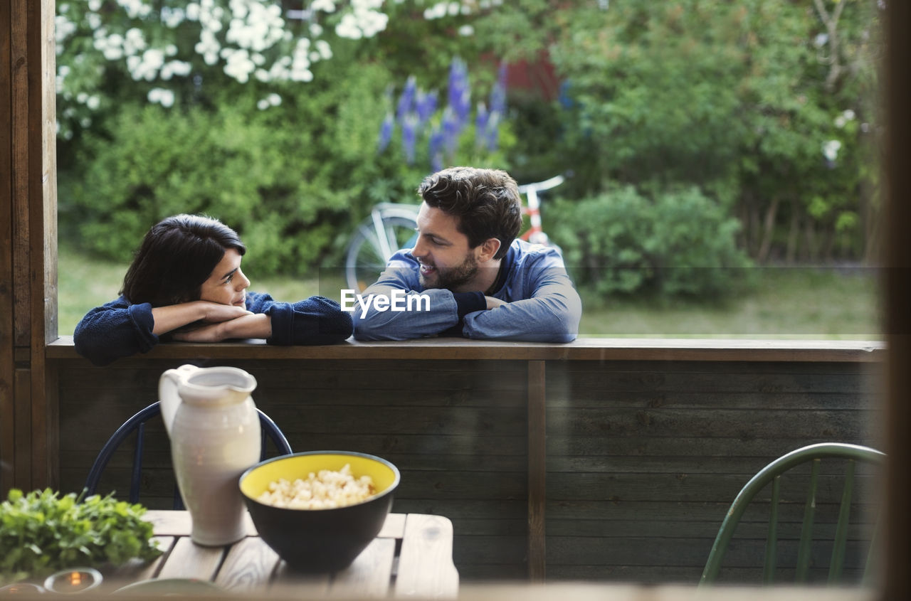 Loving couple looking at each while leaning on log cabin