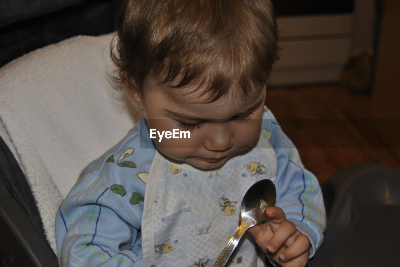 Close-up of cute boy playing with spoon at home