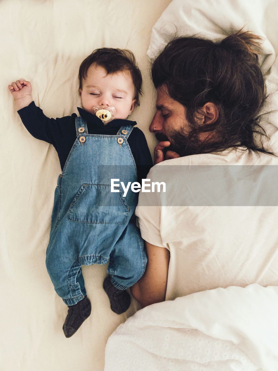 High angle view of father and daughter sleeping on bed