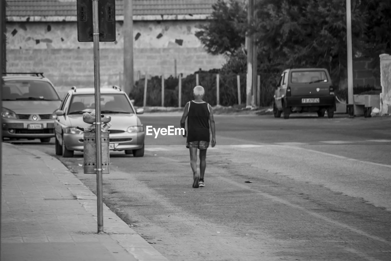 FULL LENGTH REAR VIEW OF MAN WALKING ON STREET
