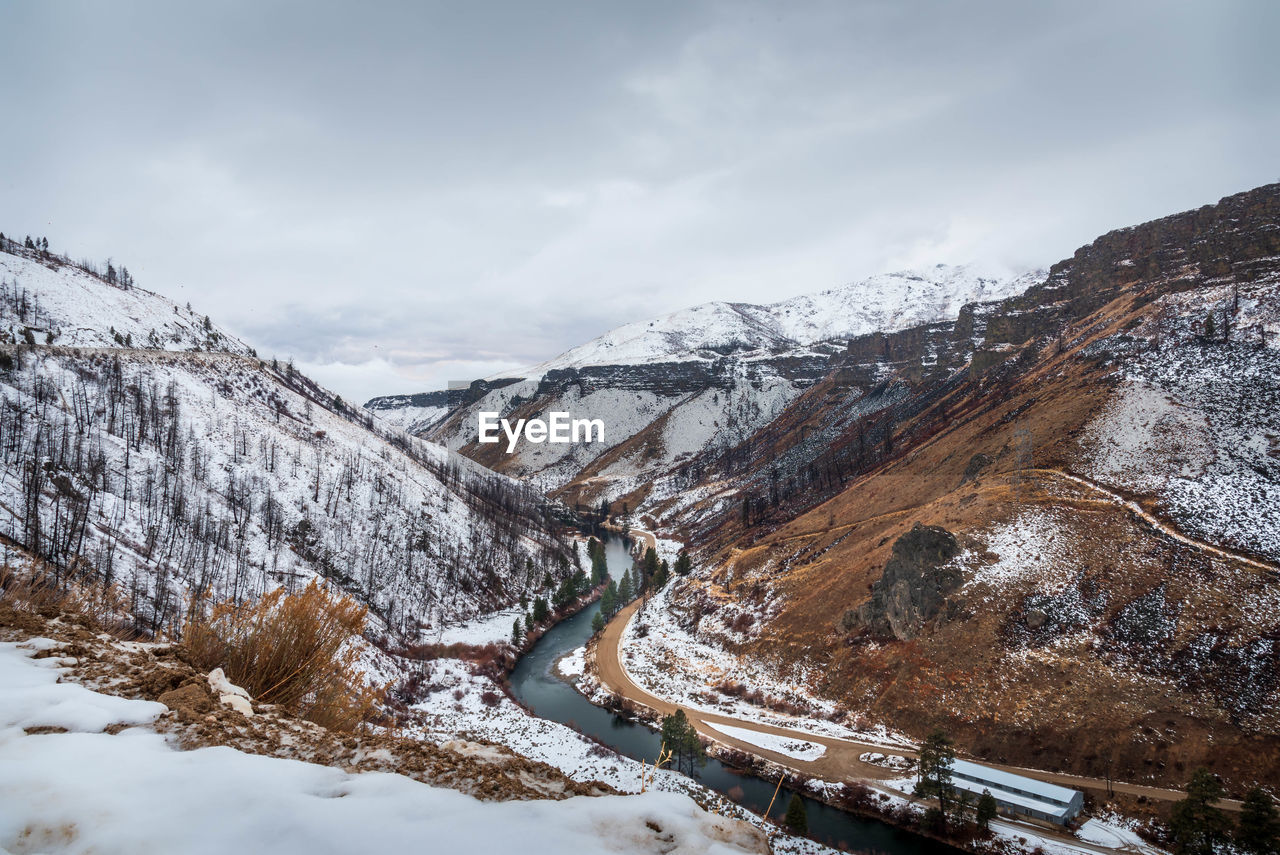 Aerial view of river flowing amidst snowcapped mountains