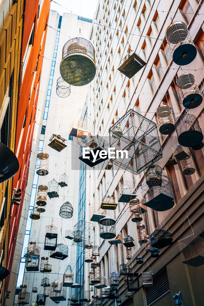 Low angle view of birdcages hanging amidst buildings in city