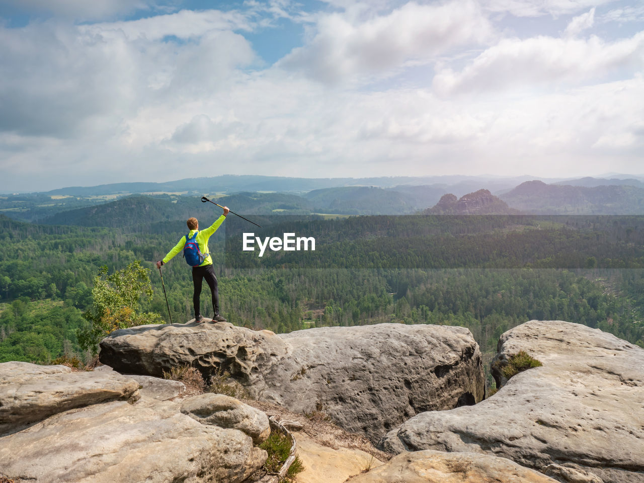 Mountain trail, in sandstone rocky hills. man wearing backpack and sunglasses, using trekking sticks