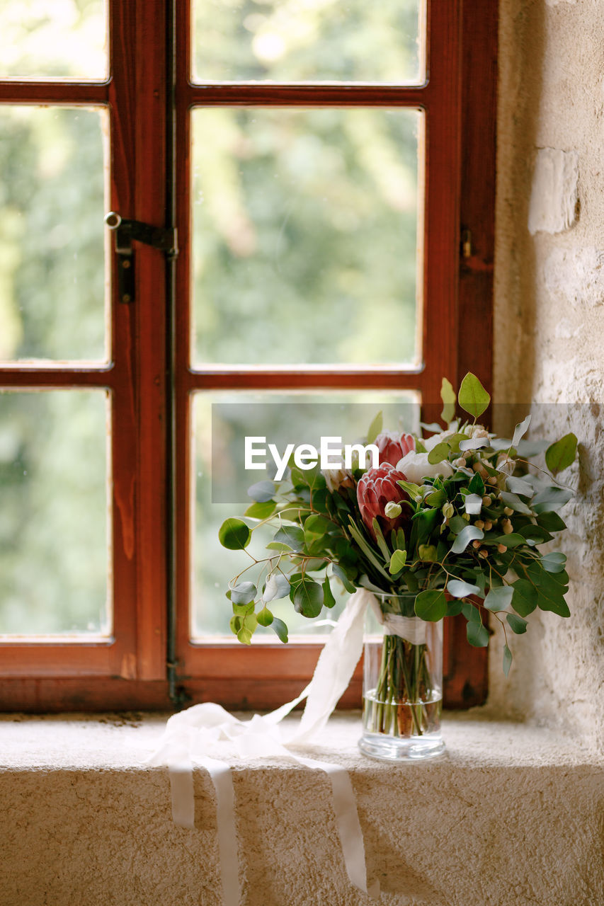 FLOWER VASE ON WINDOW SILL AGAINST WALL