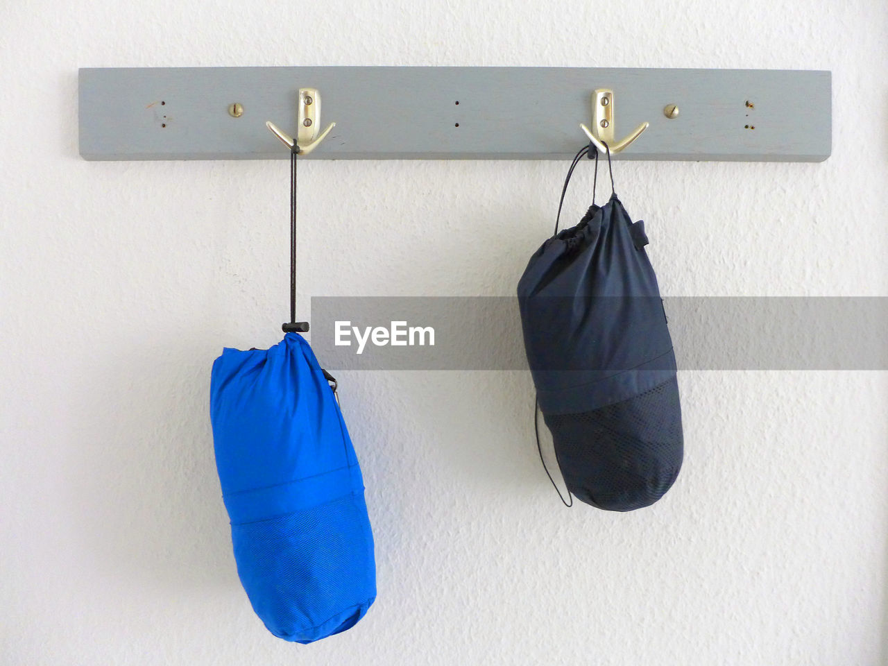 Boxing bags hanging on hooks against wall at home