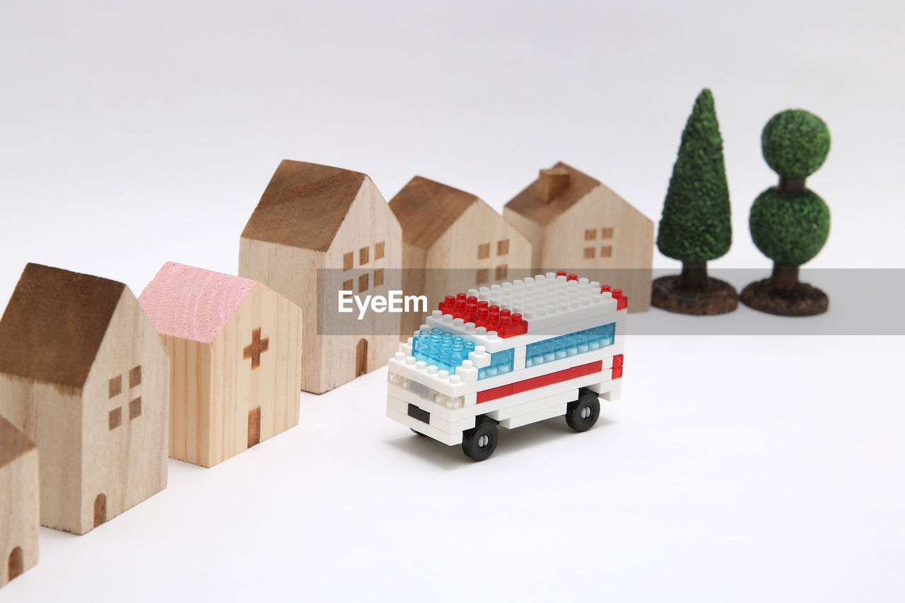 Close-up of toy ambulance and model houses on white background
