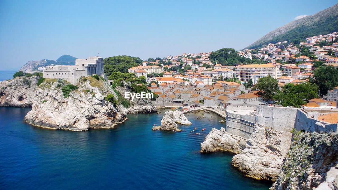 Residential district by sea against clear sky