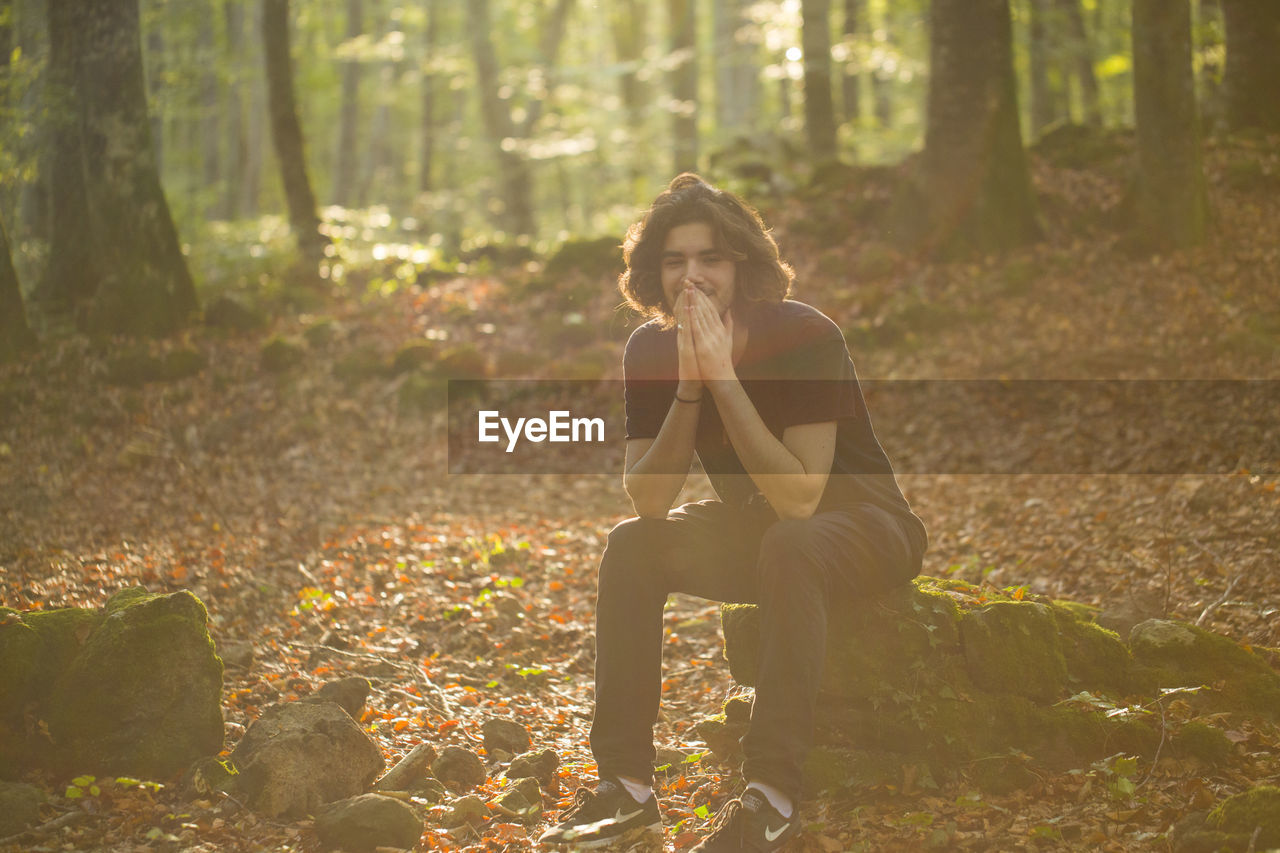 Young man sitting in forest