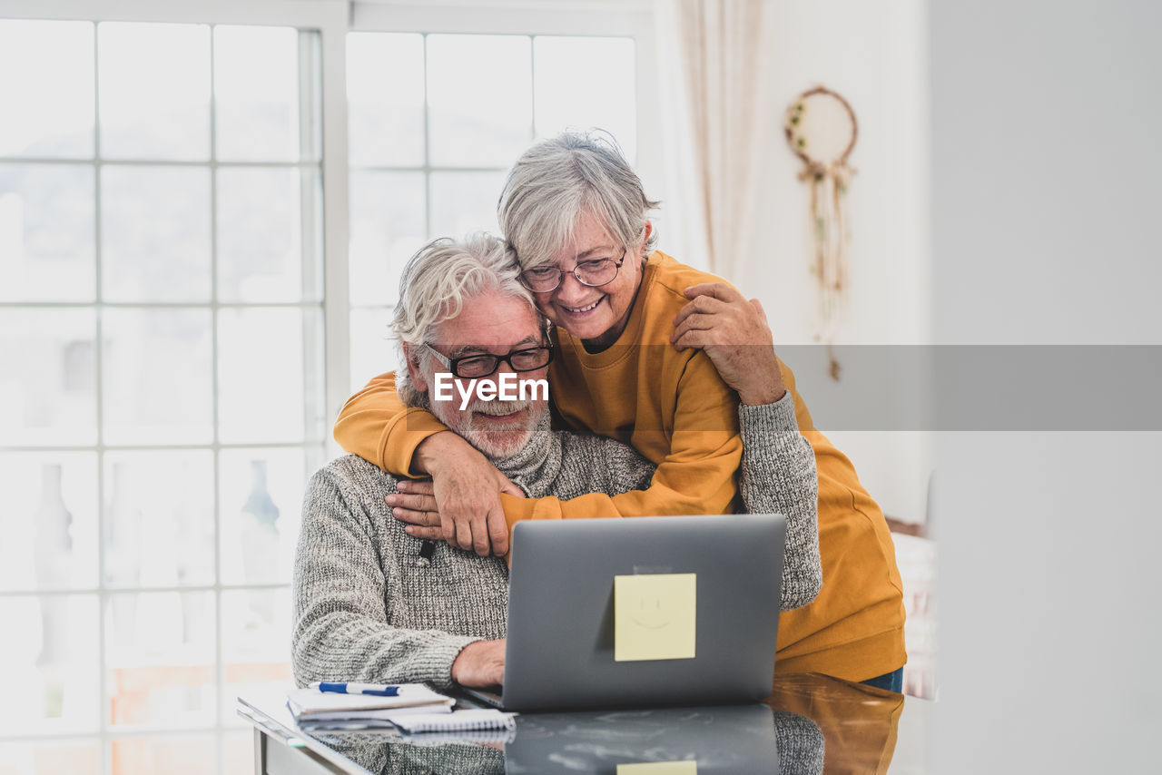 Smiling couple embracing while talking on video call at home